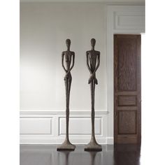 two statues are standing next to each other in front of an open door and another one is sitting on the floor