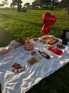 a table with cake and desserts on it in the grass at a park setting