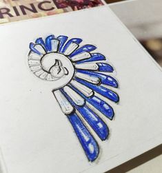 a drawing of a blue and white headdress on a piece of paper next to some books