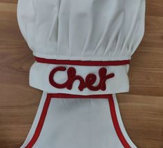 a chef's hat with the word chef embroidered on it, sitting on top of a wooden table