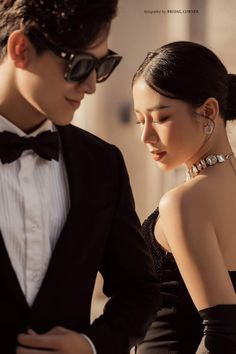 a young man and woman in formal wear looking at each other's chests