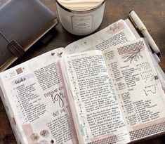 an open bible on top of a wooden table next to a cup of coffee and a pen