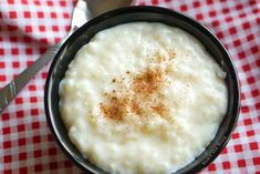 a bowl filled with mashed potatoes on top of a red and white checkered table cloth