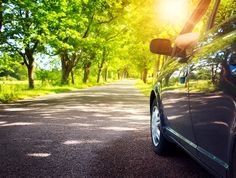 a car parked on the side of a road with trees in the background and sunlight shining through the windshield