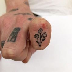 a person with a flower tattoo on their left thumb and hand holding something in the air