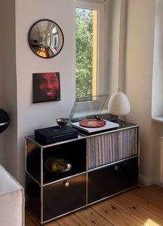 a record player sitting on top of a black cabinet in front of a large window