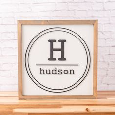 a wooden frame with the word hudson on it in front of a white brick wall