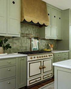 a kitchen with green cabinets and an oven in the center, along with a white counter top