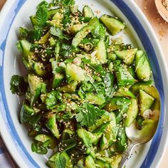 a bowl filled with green vegetables and topped with sesame seeds