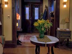 a vase with yellow flowers sitting on top of a table in a living room next to a couch