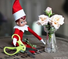 an elf is sitting on a table with flowers and scissors