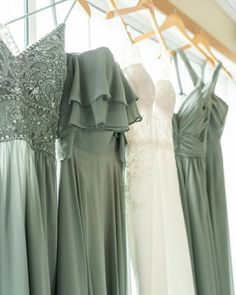 bridesmaid dresses hanging in the window with their wedding gowns on hangers