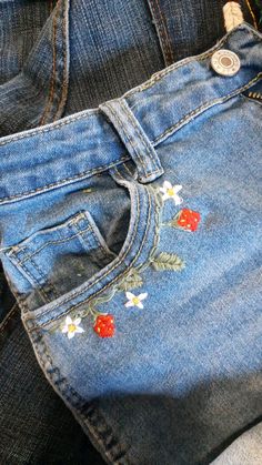 jeans with embroidered flowers on them sitting in the back pocket of someone's pants