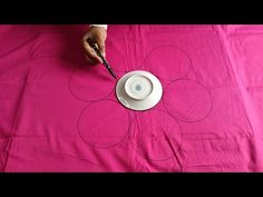 a person is cutting out circles on a pink table cloth with a knife and fork