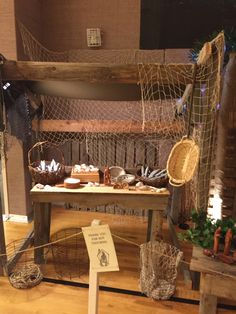 a table with baskets and other items on it in front of a wooden structure that has a net hanging from the ceiling