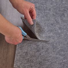 a person cutting fabric with scissors on top of it and another piece of felt in the background