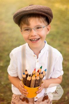 a young boy holding a bucket full of pencils