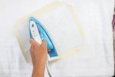 a person using an iron on top of a sheet of paper