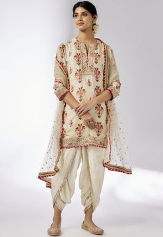 This pretty ensemble in floral jaal, combines gota and dori buttis with an intricate border embroidery. The short kurta with a dhoti embroidered in sequins and gold thread, adds a feminine grace. Off White Saree Set With Gota Work, Traditional Cream Sharara With Floral Embroidery, Traditional Drape Sets With Floral Embroidery In Cream, Cream Sets With Floral Embroidery And Traditional Drape, White Anarkali Sherwani With Floral Embroidery, Festive Off-white Gota Work Sets, Cream Salwar Kameez With Gota Work, Traditional Cream Salwar Kameez With Gota Work, Cream Kurta With Gota Work In Traditional Style