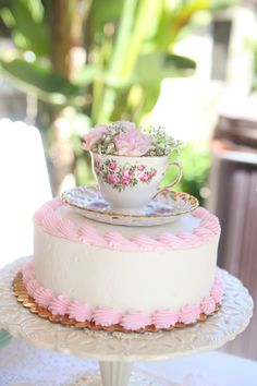 a three layer cake with pink icing and flowers on top is sitting on a table