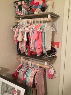 a closet filled with lots of baby clothes and toys next to a wall mounted shelf