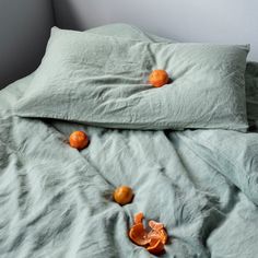 an unmade bed with two oranges on it