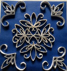 an intricately designed piece of metal on a blue cloth with silver filigrees