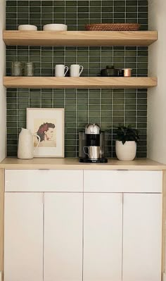 a shelf with some cups on top of it in a room that has green tiled walls