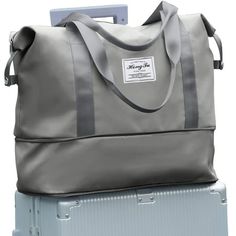 a large gray bag sitting on top of a piece of luggage