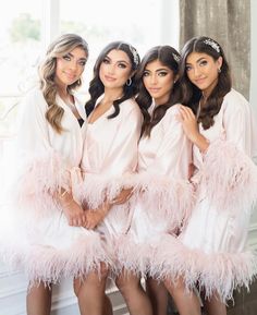 the bridesmaids are dressed in pink robes and headpieces with feathers on them