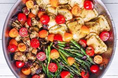 a pan filled with chicken, tomatoes and asparagus