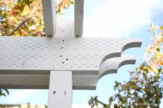 a close up of a white wooden structure with trees in the backgrouds