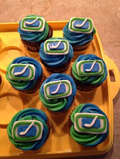 cupcakes with green and blue frosting on a yellow tray in the shape of a letter