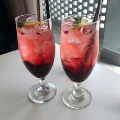 two glasses filled with red liquid and ice