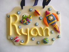 the name ryan is made out of fondant and decorated with space related items such as rockets, rocket ship, planets, and stars