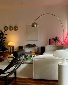 a living room filled with white furniture and lots of lights on the wall above it