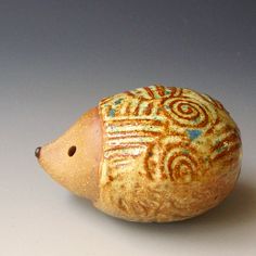 a ceramic figurine shaped like a hedgehog on a white surface with blue and red designs