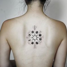 the back of a woman's neck with an intricate tattoo design on her left shoulder