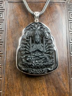 a silver buddha pendant sitting on top of a wooden table