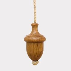 a wooden object hanging from a rope on a white background in the shape of a vase