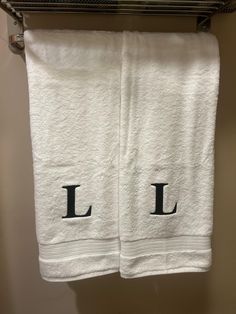 two white towels with the letters l and l on them hanging from a towel rack