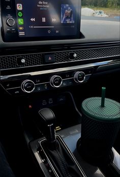 the interior of a car with an entertainment system and coffee cup on the dash board