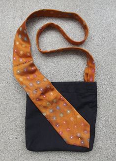 an orange and black neck tie laying on the ground