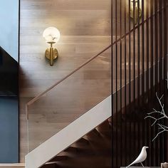 two white birds sitting on top of a wooden floor next to a stair case and light fixture