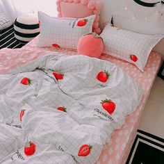 a bed covered in pink and white sheets with strawberries on it's covers