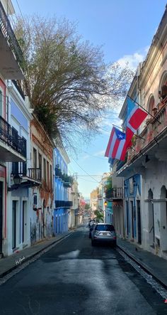 a car is parked on the street in front of buildings with flags hanging from balconies