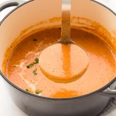 a ladle in a pot filled with tomato soup