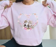 Introducing our whimsically Kitten Heart Sweatshirt - a true nod to the vintage 90s era with a delightful touch of French charm! Adorned with adorable kittens in a 90s portrait style, this sweater is your ticket to cuteness overload. Whether you're a feline enthusiast or simply appreciate the whimsy of vintage-inspired fashion, this sweater is your purr-fect companion for adding a touch of playfulness to your wardrobe. Get ready to make a statement that's both timeless and utterly meow-gical! This sweatshirt also makes a wonderful gift for cat moms and cat lovers alike. The floral heart design makes it especially purr-fect for Valentine's Day! * 50% cotton, 50% polyester * Pre-shrunk * Classic fit, size up for oversized fit * 1x1 athletic rib knit collar with spandex * Air-jet spun yarn wi Coquette Kitten, Coquette Cat, Cute Cottagecore, Cat Vintage, Adorable Kittens, Cottagecore Coquette, Sweatshirt Trendy, 90s Era, Vintage Inspired Fashion