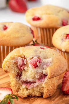 strawberry muffins cut in half on a cutting board with strawberries around them