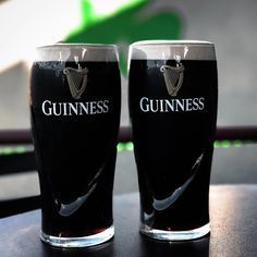 two guinness glasses sitting on top of a table